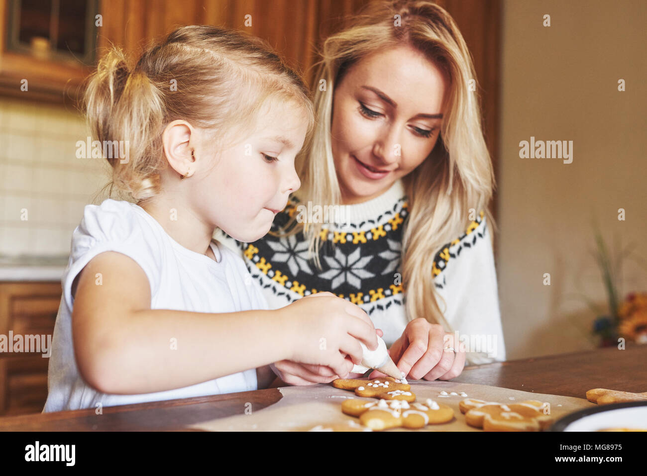 Mamma e figlia decorare i biscotti di Natale con zucchero bianco Foto Stock