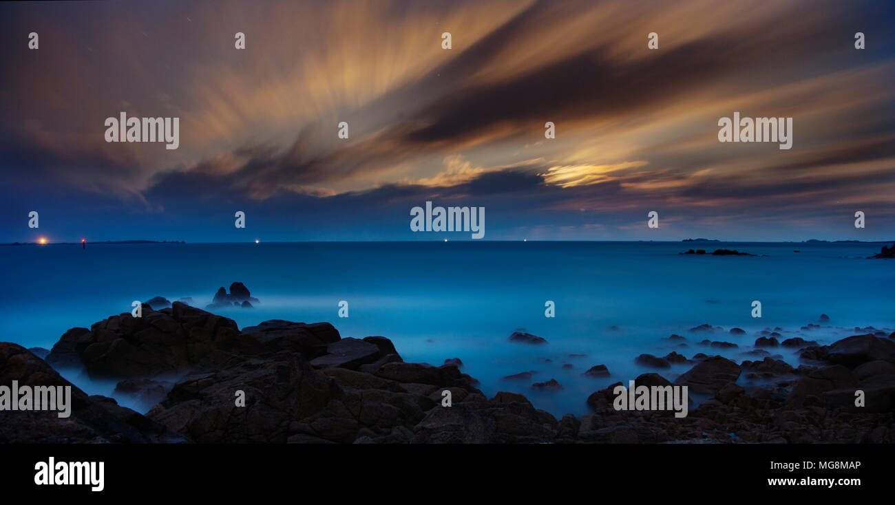 La luna tramonta dietro il cloud a ovest delle Isole Scilly nelle prime ore del mattino Foto Stock