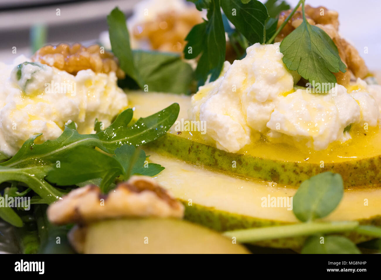 Un sano un pasto leggero o uno snack costituito da fette di pere e noci, morbido formaggio di capra, crescione e rucola guarnito con olio d'oliva. Foto Stock