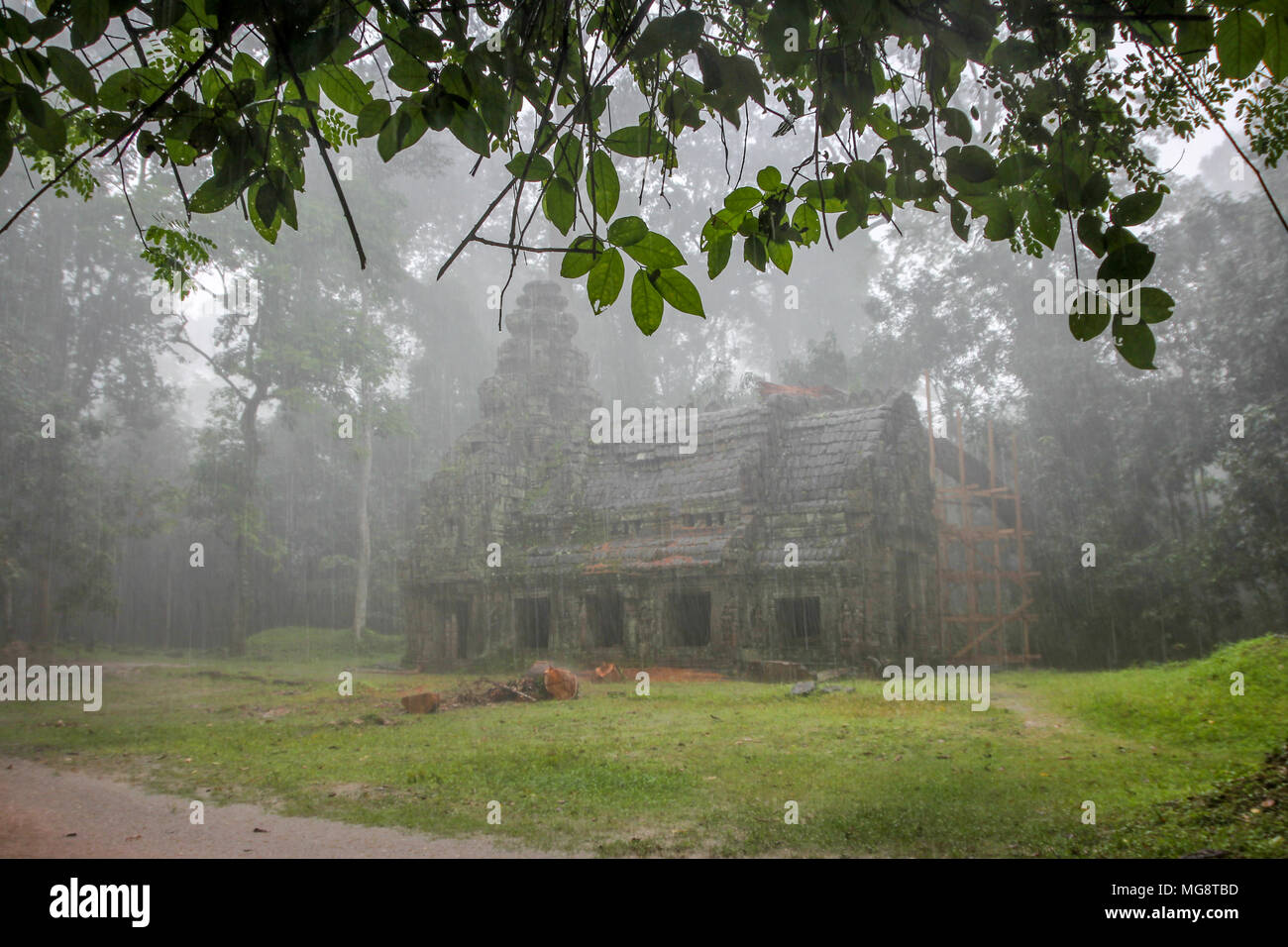 Edificio locale in fase di ristrutturazione all'interno di Ta Prohm tempio complesso Angkor Cambogia in un acquazzone. Foto Stock