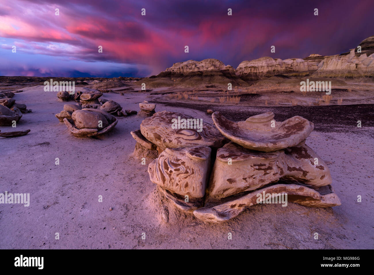 Bisti o De-Na-Zin Wilderness Area o formazioni rocciose di badlands al tramonto con nubi tempesta sullo sfondo, New Mexico, USA Foto Stock