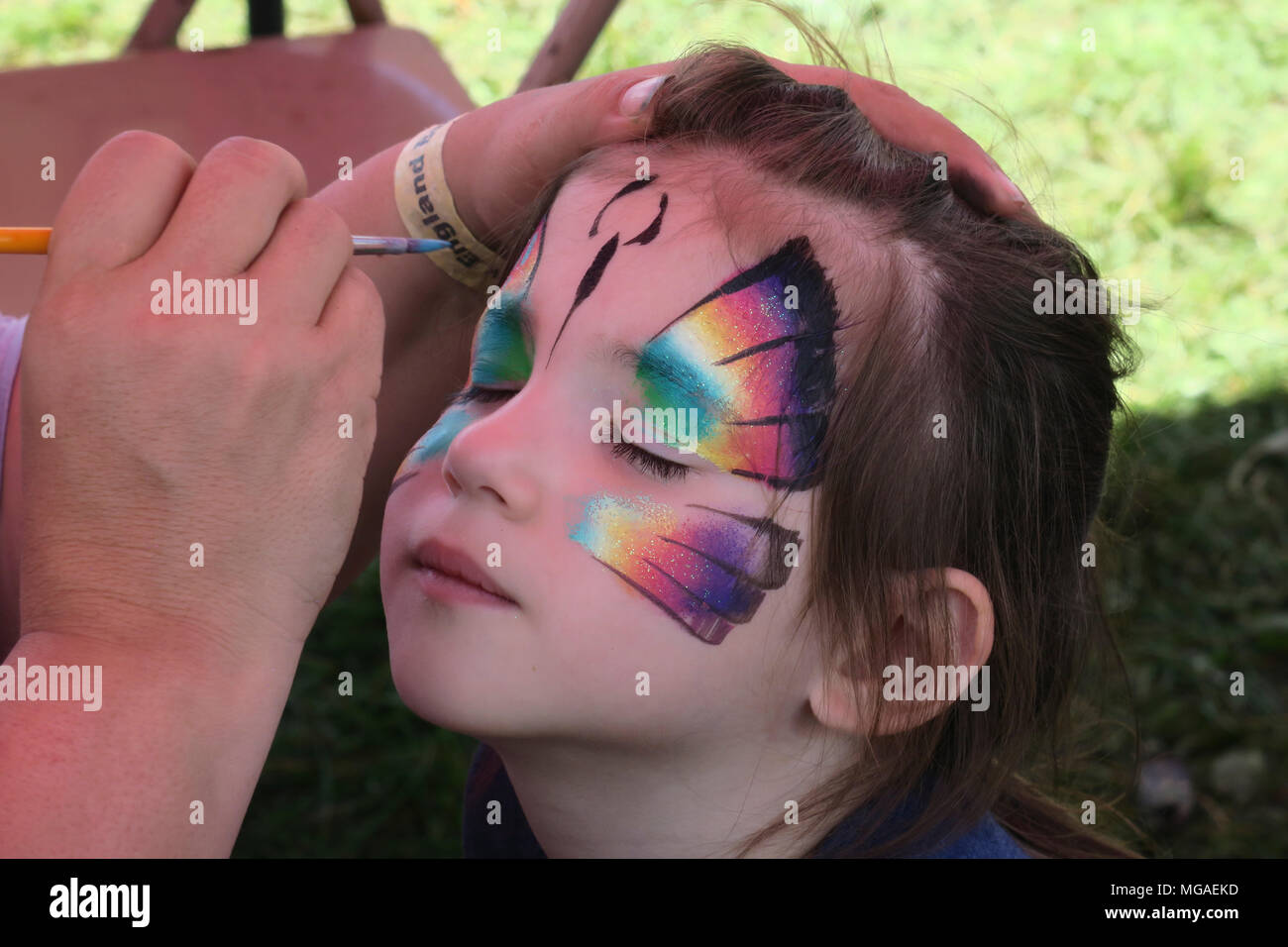 Quattro-anno-vecchia ragazza avente la sua faccia dipinta con una farfalla e un carnevale estivo Foto Stock