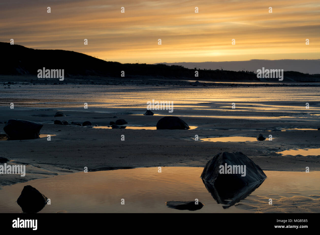 Marske spiaggia al tramonto. Parco eolico a distanza Foto Stock