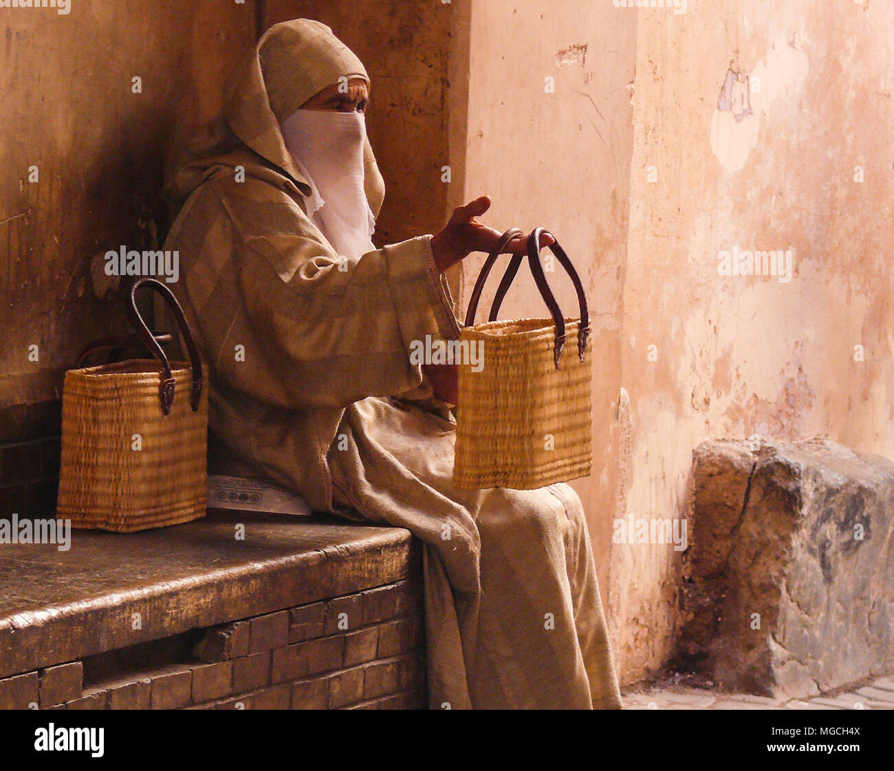 Venditore ambulante, seduto sulla parete, sacchetti di vendita nel souk, Marrakech, Marocco. Foto Stock