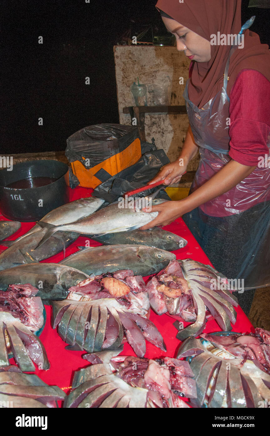 Donna Malay pulizia del pesce al mercato notturno sul lungomare a Kota Kinabalu, Sabah Malaysian Borneo Foto Stock