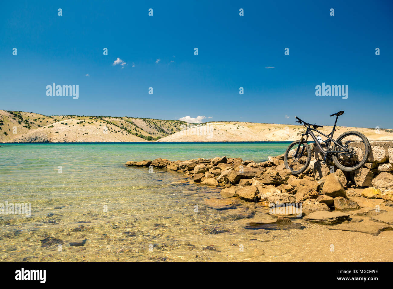 Mountain bike sopra il livello del mare, delle montagne e del cielo blu su una spiaggia rocciosa, giorno di estate paesaggio. Idea per vacanze o weekend attività sana. Fitness e spo Foto Stock