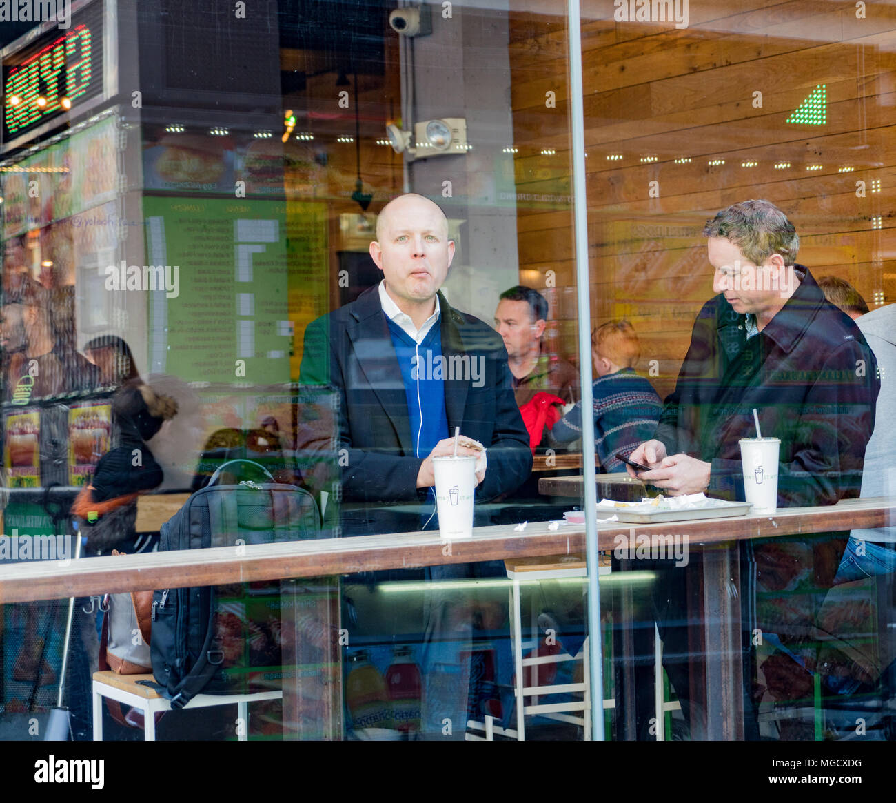 New York, Feb 14, 2018 - Persone di mangiare al bar al coperto visibile attraverso la finestra di street Foto Stock