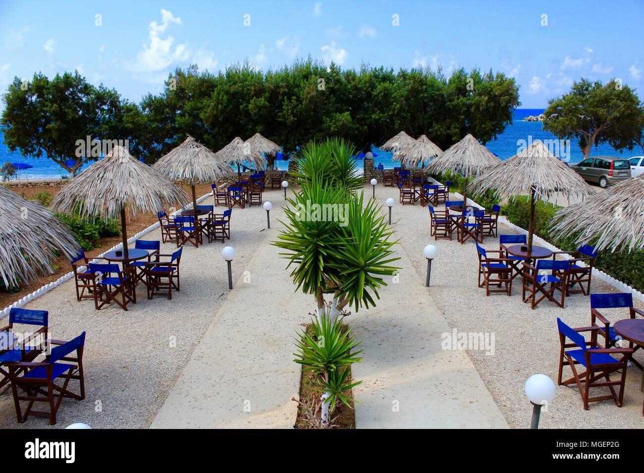 Complesso balneare con sedie blu e l'ombrello di ordinata e legno può creare simmetrie con piante al centro dell'inquadratura Foto Stock