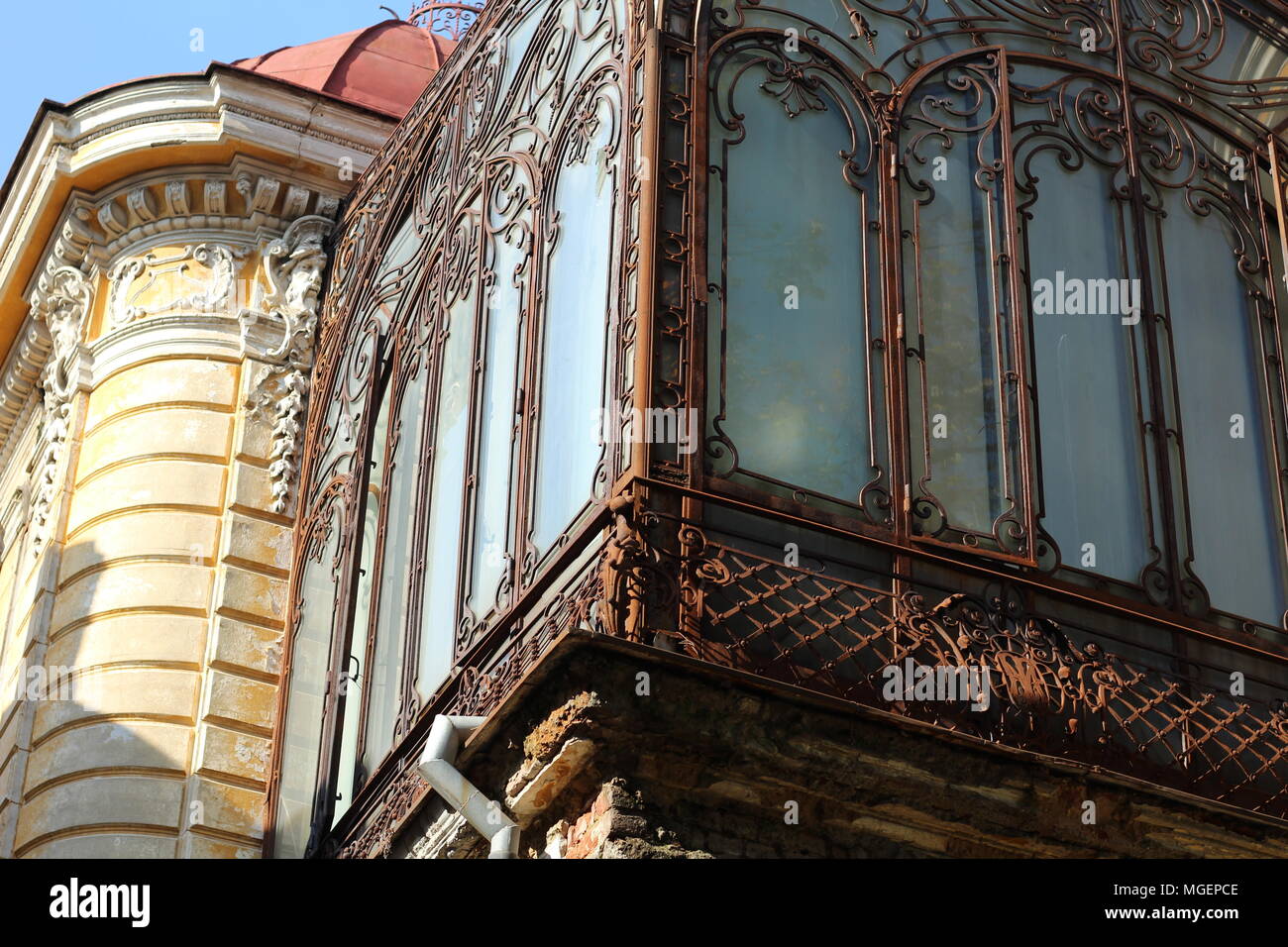 Vecchio balcone con veranda e smerigliato blu windows sull'angolo di un edificio giallo, nel centro storico di Bucarest Foto Stock