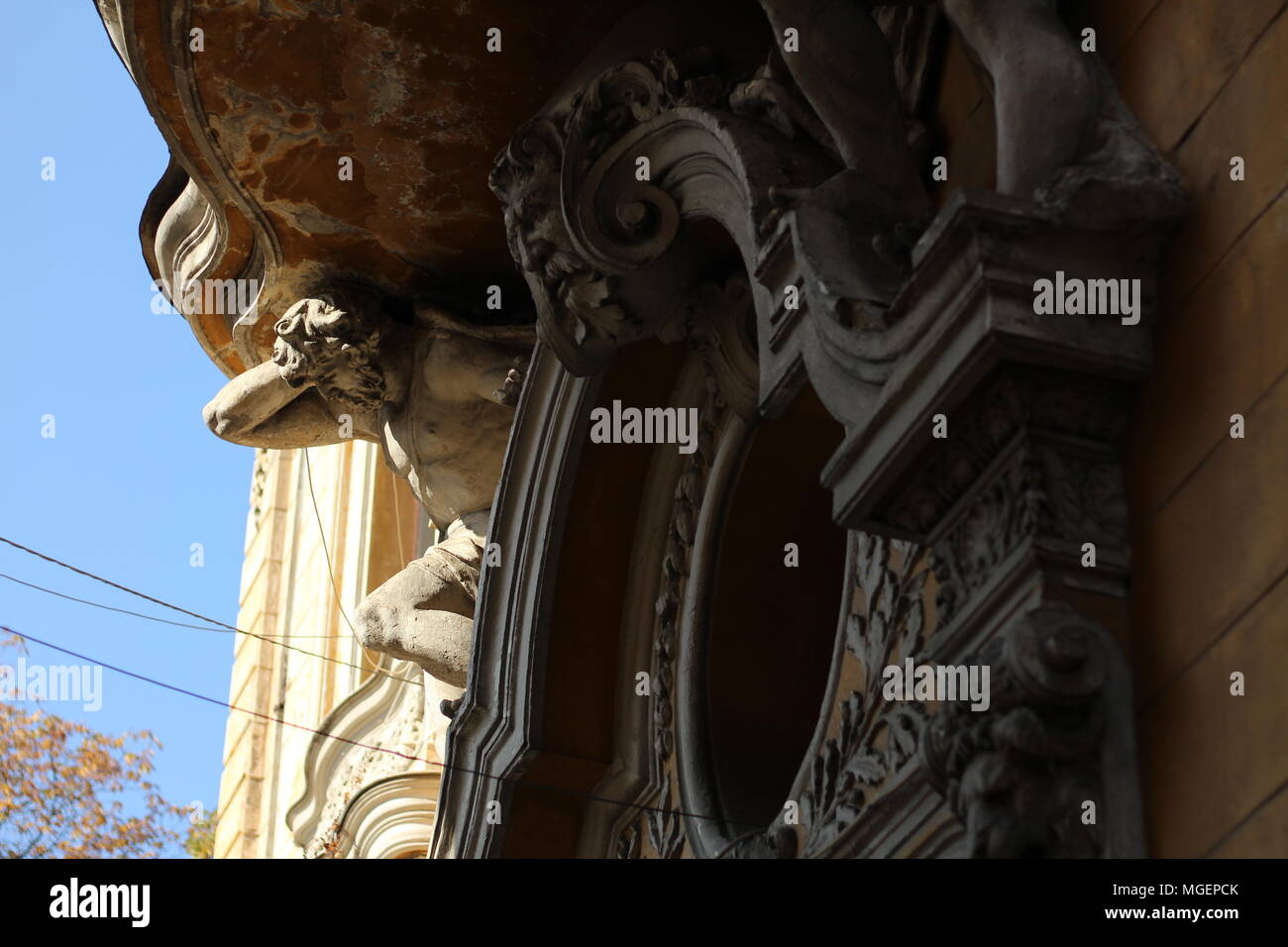 Capitale con una statua illuminata dal sole mentre il resto del balcone rimane in ombra in un edificio nel centro storico di Bucarest Foto Stock