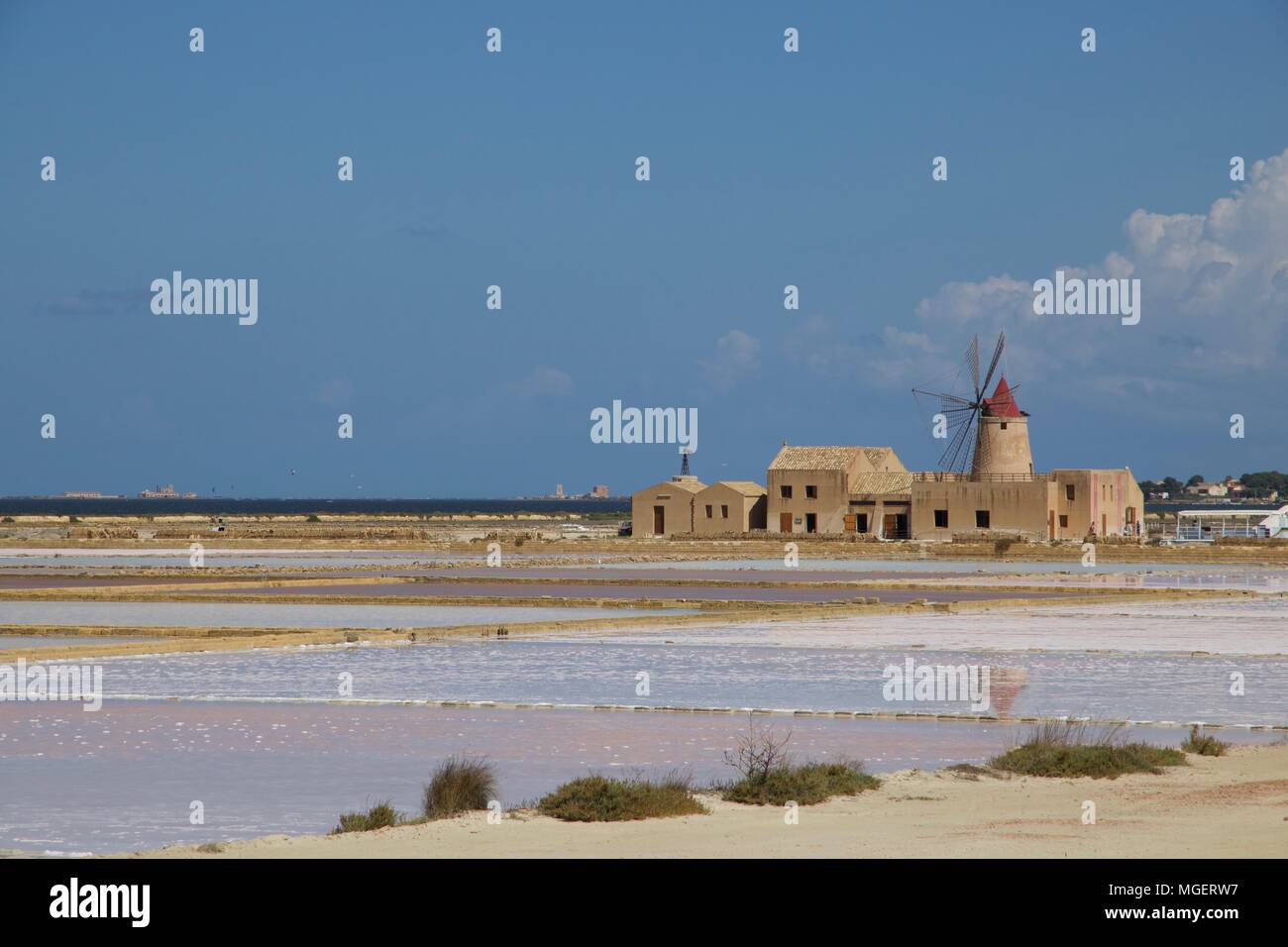 Un faro di bianco con un tetto rosso nel mezzo delle saline di Marsala in Sicilia, l'Italia, in una bella giornata di sole con un cielo blu che riflette Foto Stock
