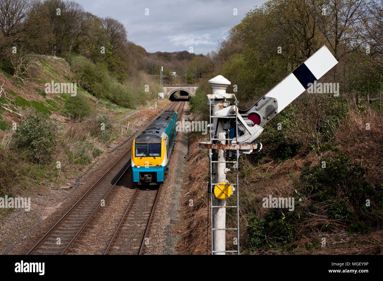 Un Arriva Trains Wales classe 175 treno passa un semaforo meccanica segnale ferroviario a Frodsham Junction, Cheshire Foto Stock