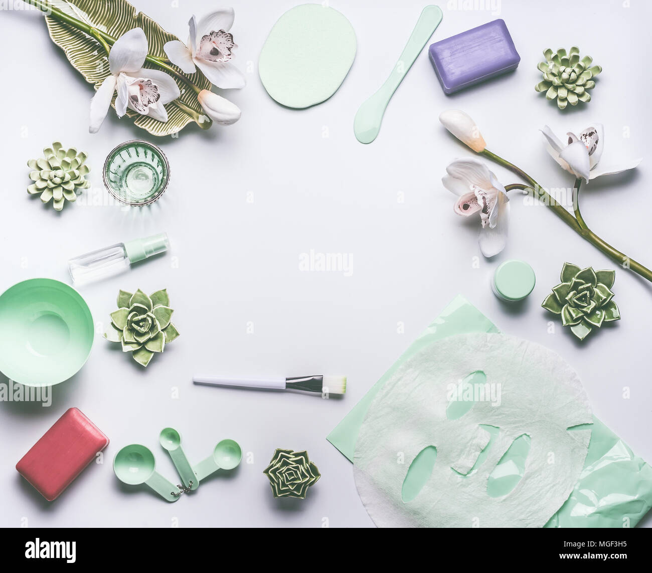 A base di erbe naturali per la cura della pelle impostazione cosmetici con fiori di orchidea, accessori e del viso foglio calmante maschera su sfondo bianco, vista dall'alto, il telaio, la piana Foto Stock