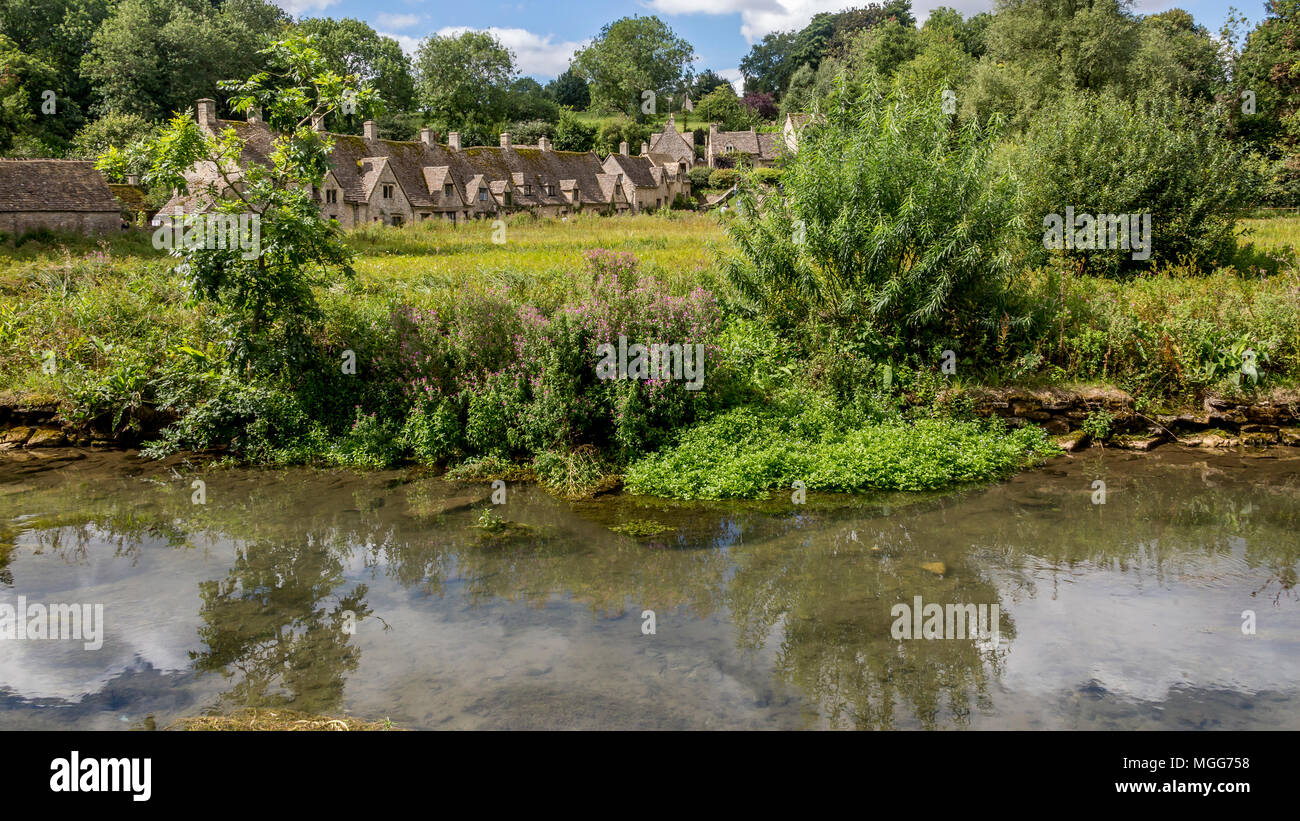 Il Fiume Coln fluisce attraverso il villaggio di Bibury il famoso Arlington fila che si riflette nelle sue acque tranquille Foto Stock