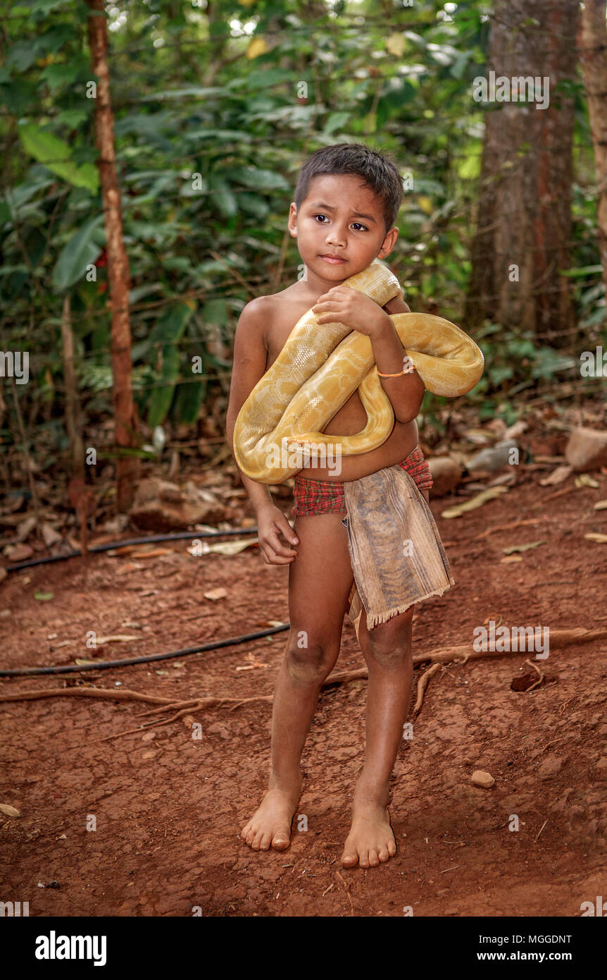 Piccolo Palawano filippino ragazzo sta con il suo giallo pet Albino Ball Python Python regius, avvolto intorno al suo collo in corrispondenza di Palawan Giardino Eco e nativo Foto Stock