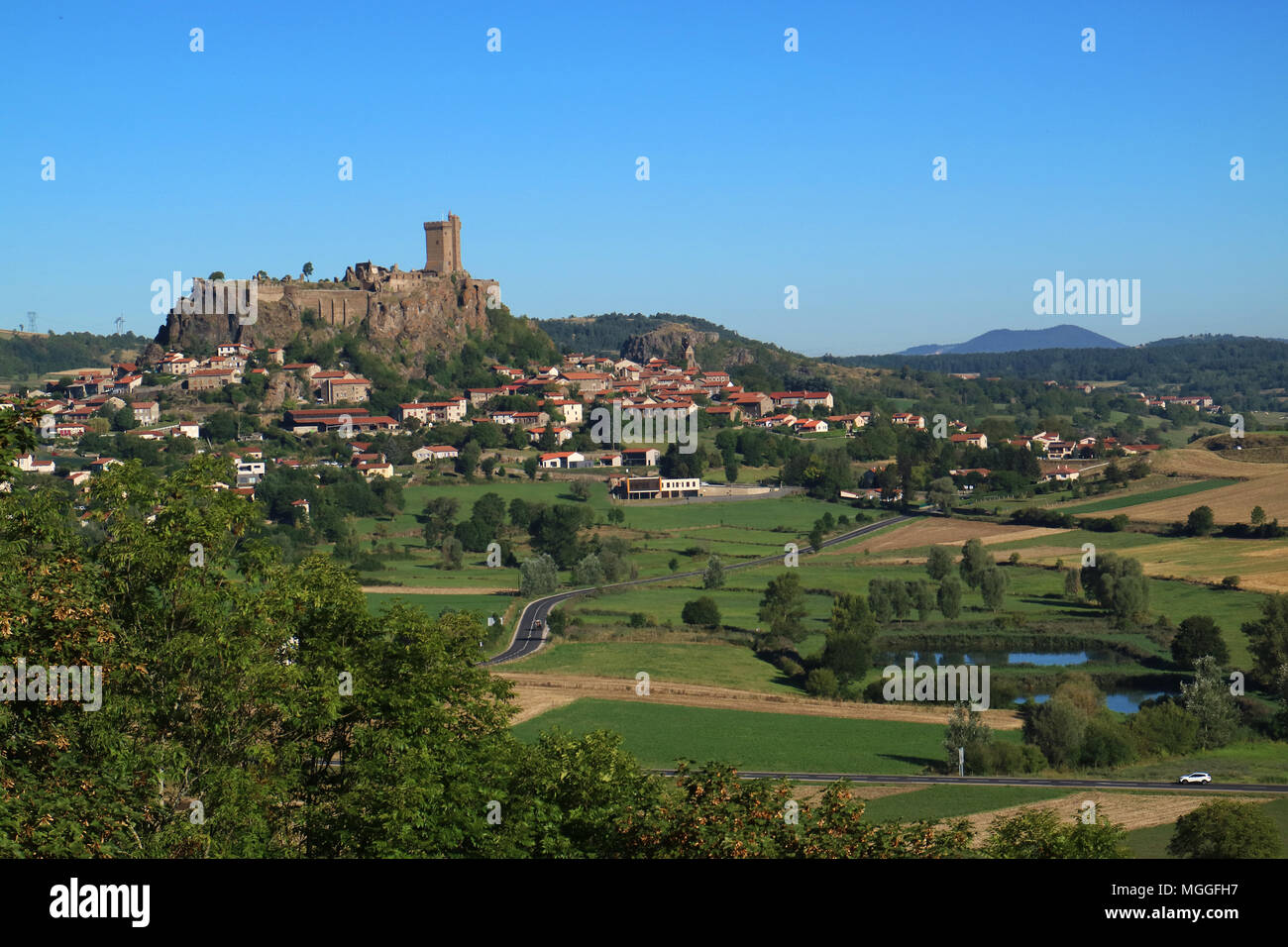 Vista della città di Polignac, vicino a Le Puy-en-Velay,dominato dal 'Fortresse de Polignac' con il suo torrione quadrato torre, 32 m di altezza, Auvergne, Francia Foto Stock