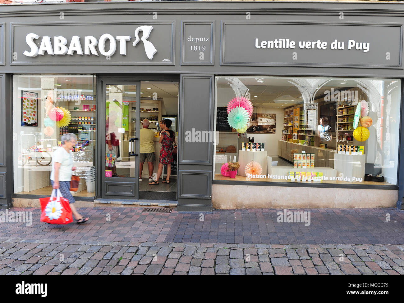 Una donna cammina dall ingresso di Sabarot cibo gourmet shop in Le-Puy-en-Velais, Francia Foto Stock