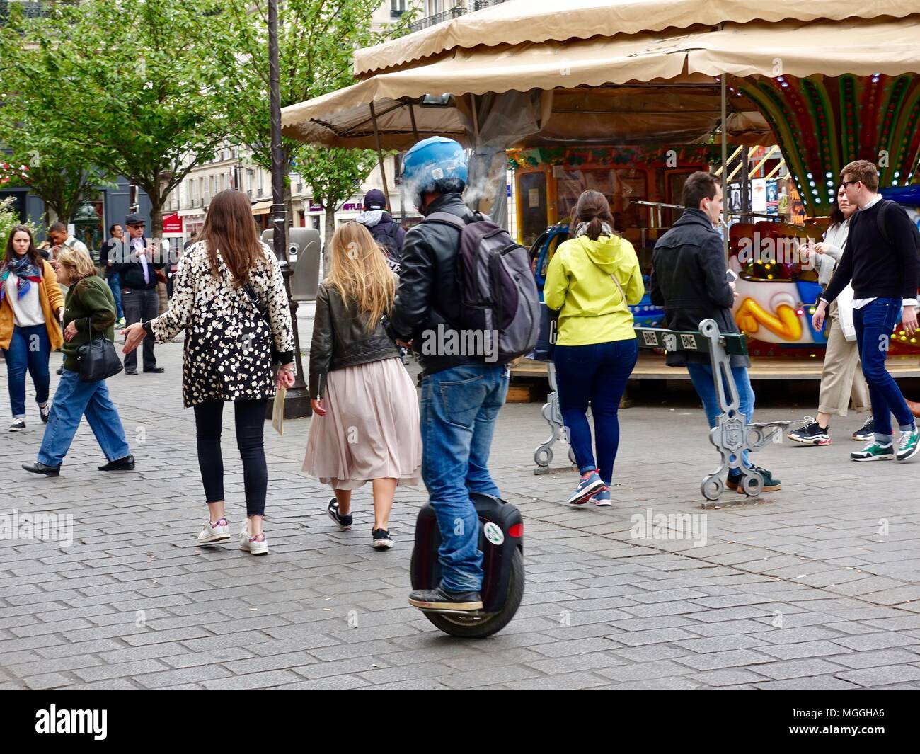 Uomo con casco, cavalcando un monociclo motorizzato, tesse attraverso la folla mentre i vapori di e-sigaretta circonda la sua testa. Parigi, Francia. Foto Stock