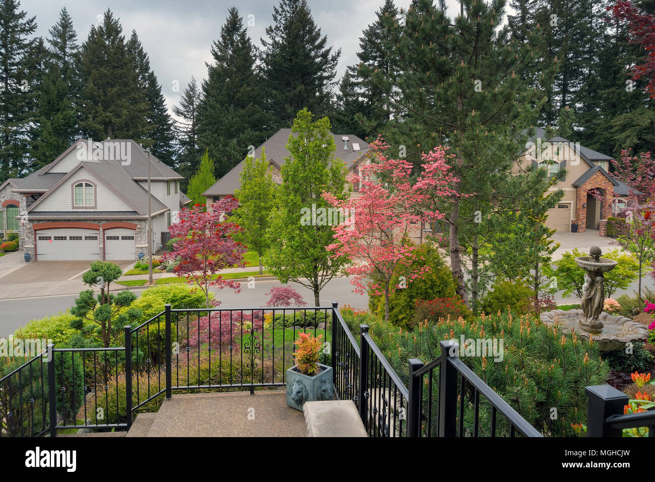 Home ingresso cortile anteriore prato giardino paesaggistico con ringhiere fontana acqua alberi fioriti e plnats nella stagione primaverile Foto Stock