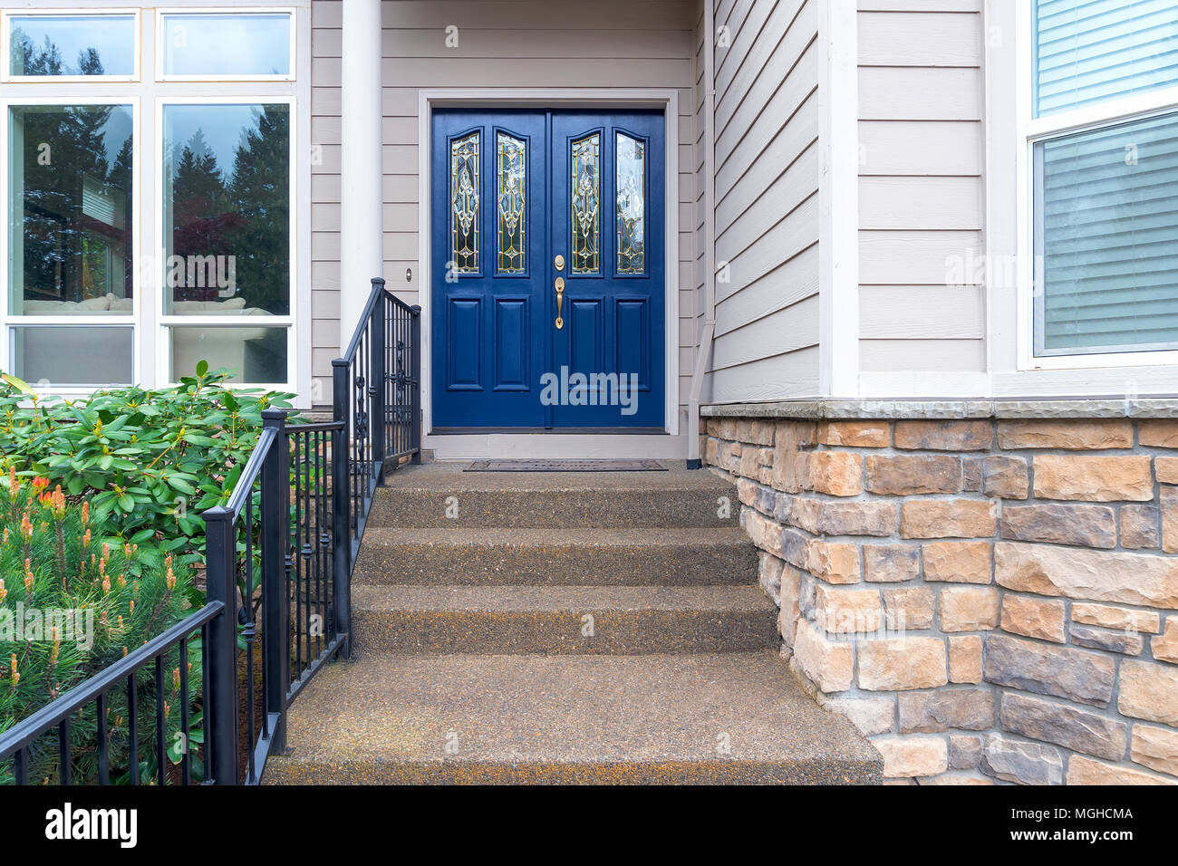 Casa ingresso anteriore con passi concreti in tondino di ferro ringhiera e blu navy porte doppie Foto Stock