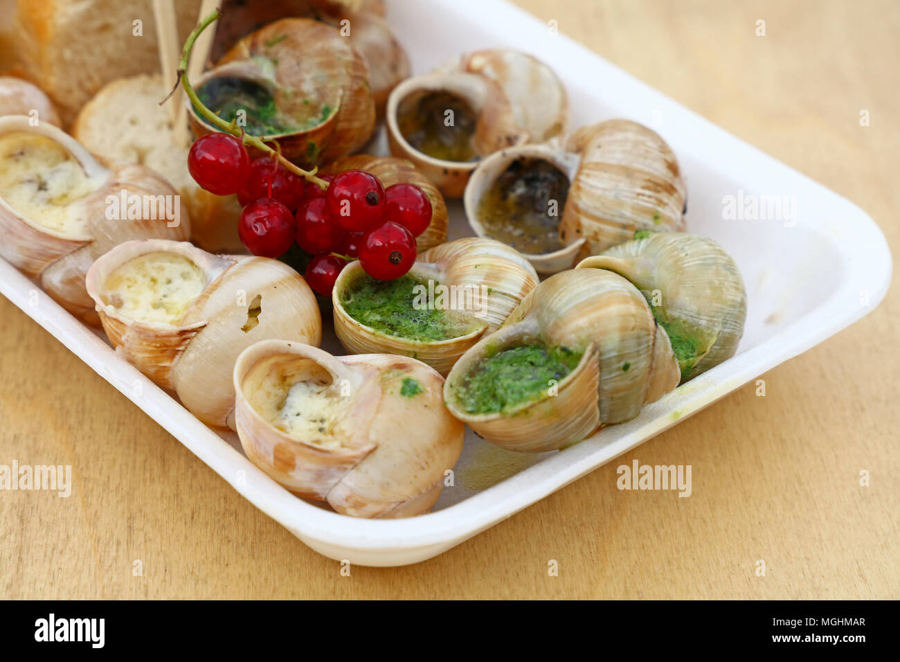 Close up street fast food take away porzione di cotto lumache escargot francese con erbe aromatiche e burro all'aglio e pane baguette, ad alto angolo di visione Foto Stock