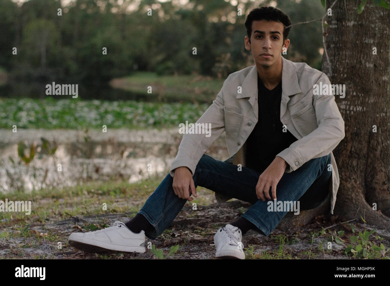 Giovane e moderno alla moda medio orientale indiano maschio modello ridendo e in posa di natura presso il parco per ritratto scatti della testa Foto Stock