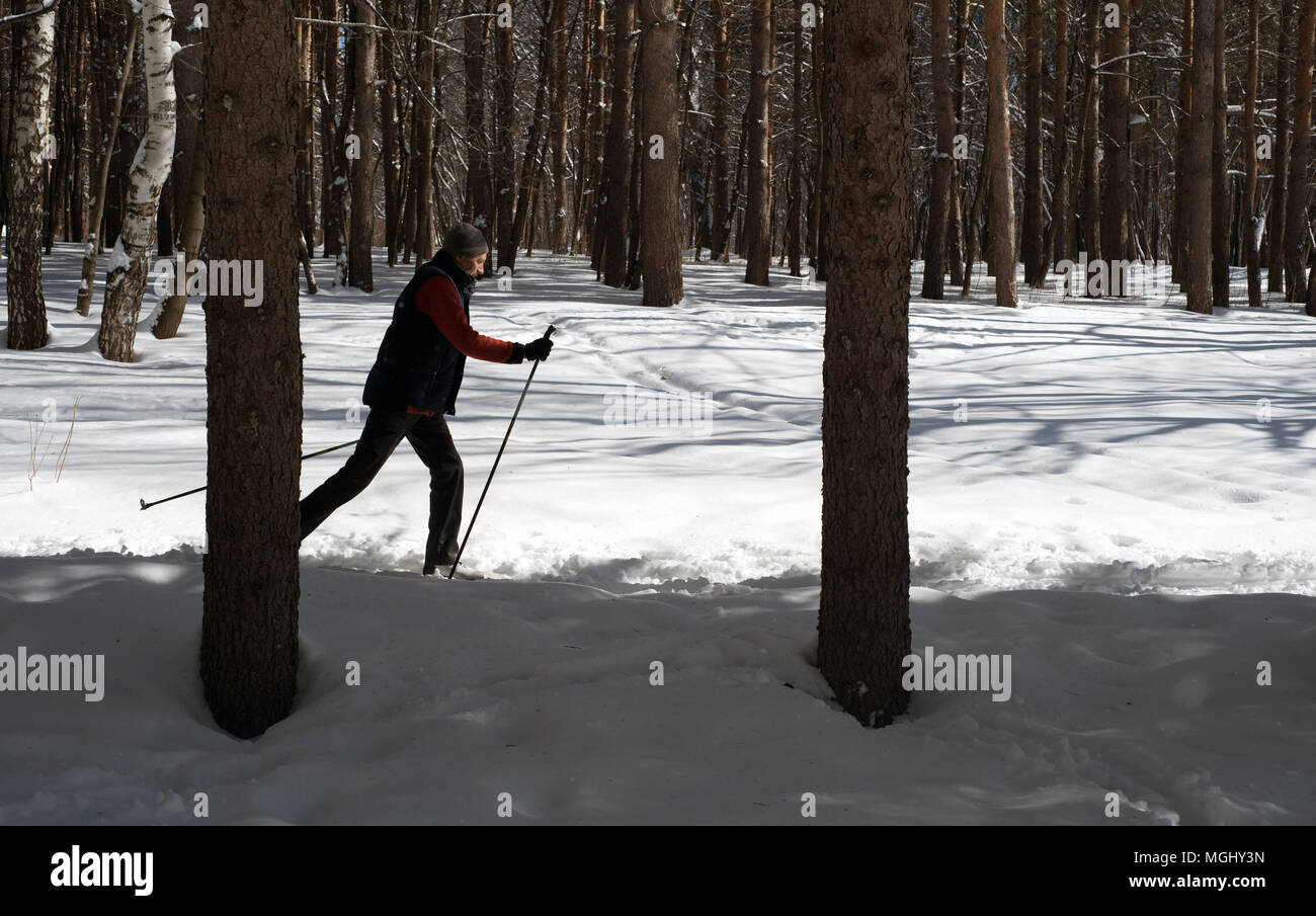 UFA, Russia 29marzo 2018 - uomo anziano cross country attraverso una pista forestale in nevicata utilizzando l'inverno sport per migliorare la sua salute mentre enjoyin Foto Stock