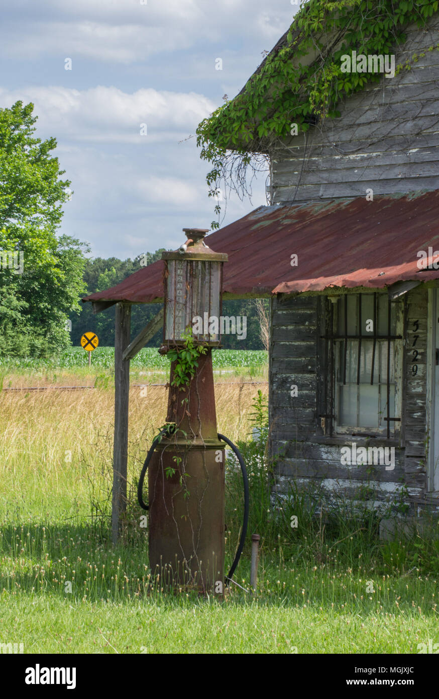 Arrugginita fuori cassetta lungo una strada di campagna; gas pompa una memoria di giorni passati. Decadimento rurale racconta una storia tra la ruggine, abbandono e overgrowth. Foto Stock