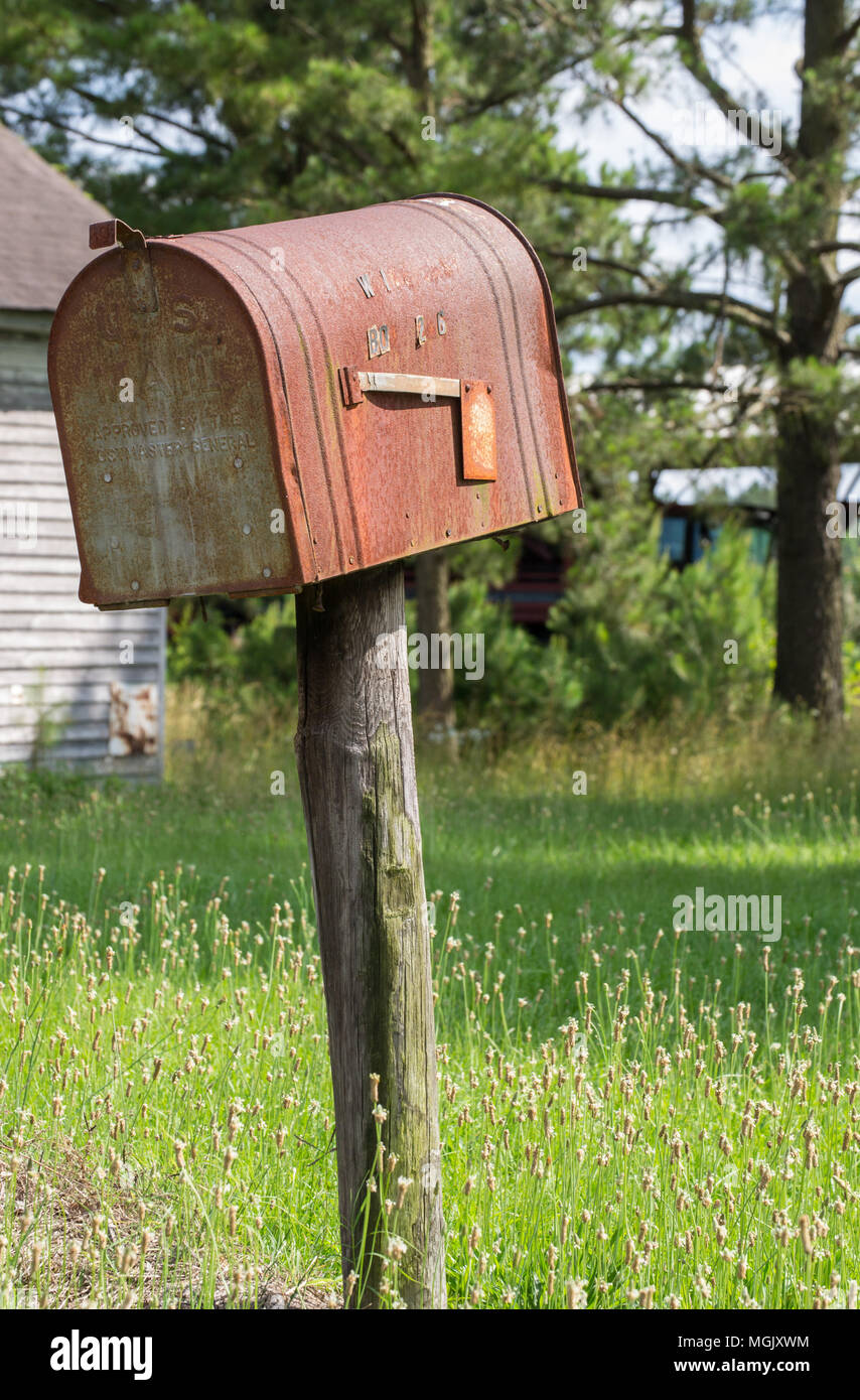 Arrugginita fuori cassetta lungo una strada di campagna; gas pompa una memoria di giorni passati. Decadimento rurale racconta una storia tra la ruggine, abbandono e overgrowth. Foto Stock