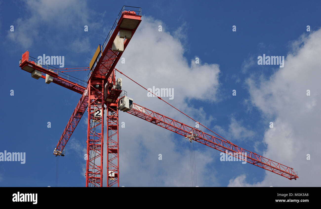 Due gru rossa nella parte anteriore di un cielo azzurro con soffici nuvole bianche Foto Stock