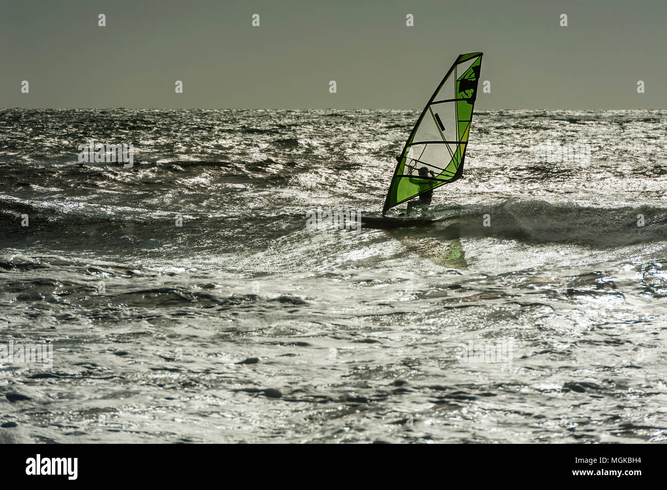 Windsurf con verde retroilluminato a vela su un mare metallico. Foto Stock