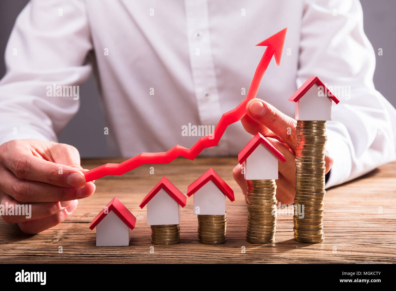 Commercianti la mano che tiene la freccia su monete impilate con modelli della casa Foto Stock