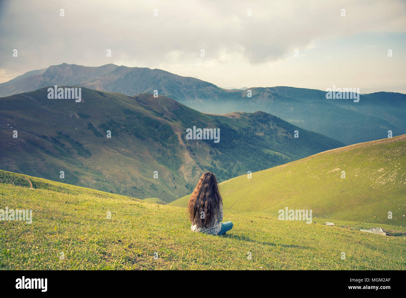 Una ragazza con lunghi capelli ricci alla ricerca sulle montagne Foto Stock