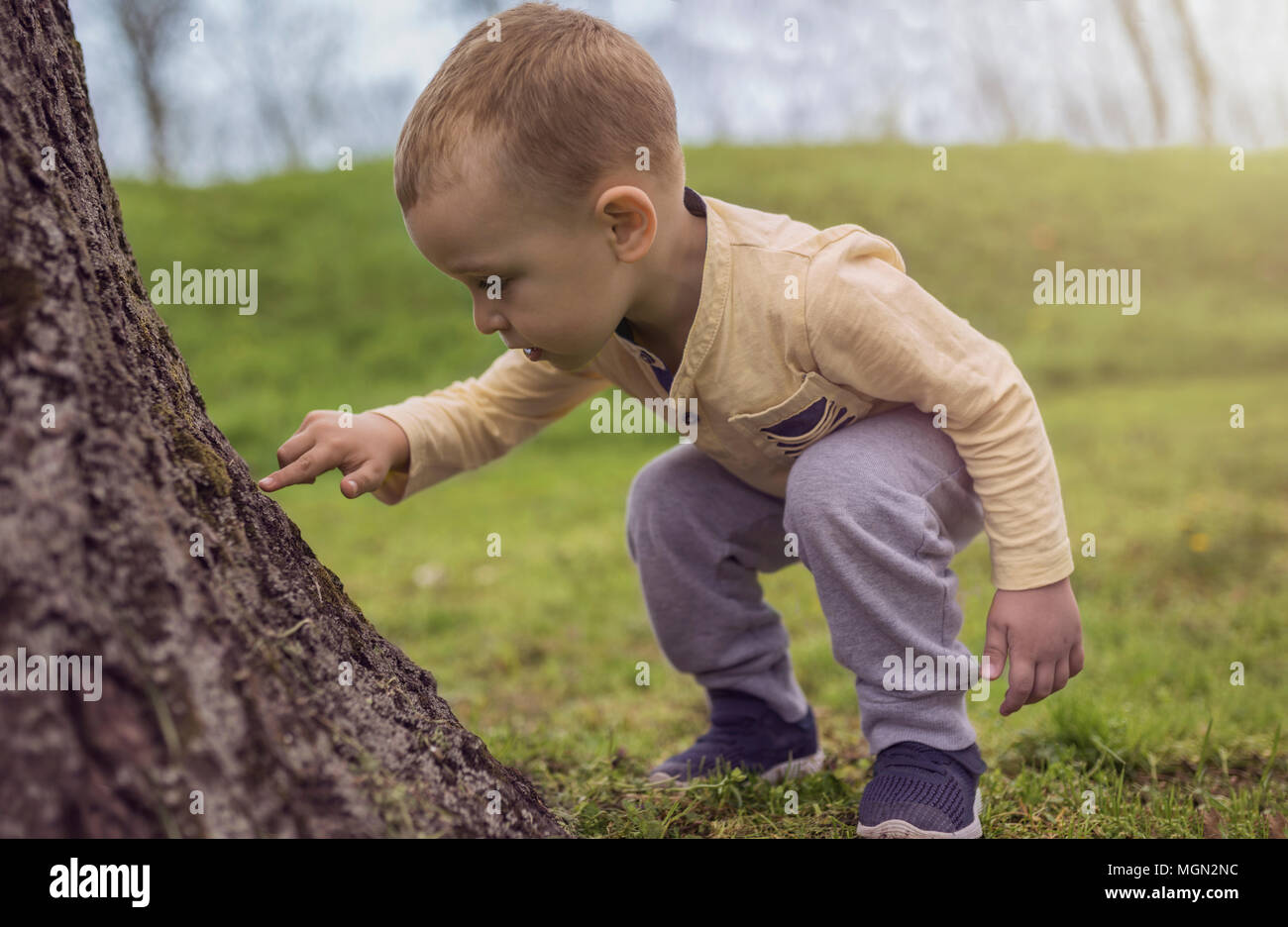 Adorable little boy divertirsi sul parco giochi. Active sport tempo libero per bambini all'aperto nel parco. Piccolo Ragazzo con gli occhi blu in giallo shirt giocando e hav Foto Stock