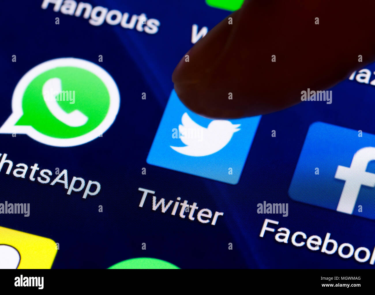 Dito che preme una icona di collegamento per caricare l'applicazione Twitter su un tablet o lo schermo dello smartphone. Pulsante di Twitter. Foto Stock