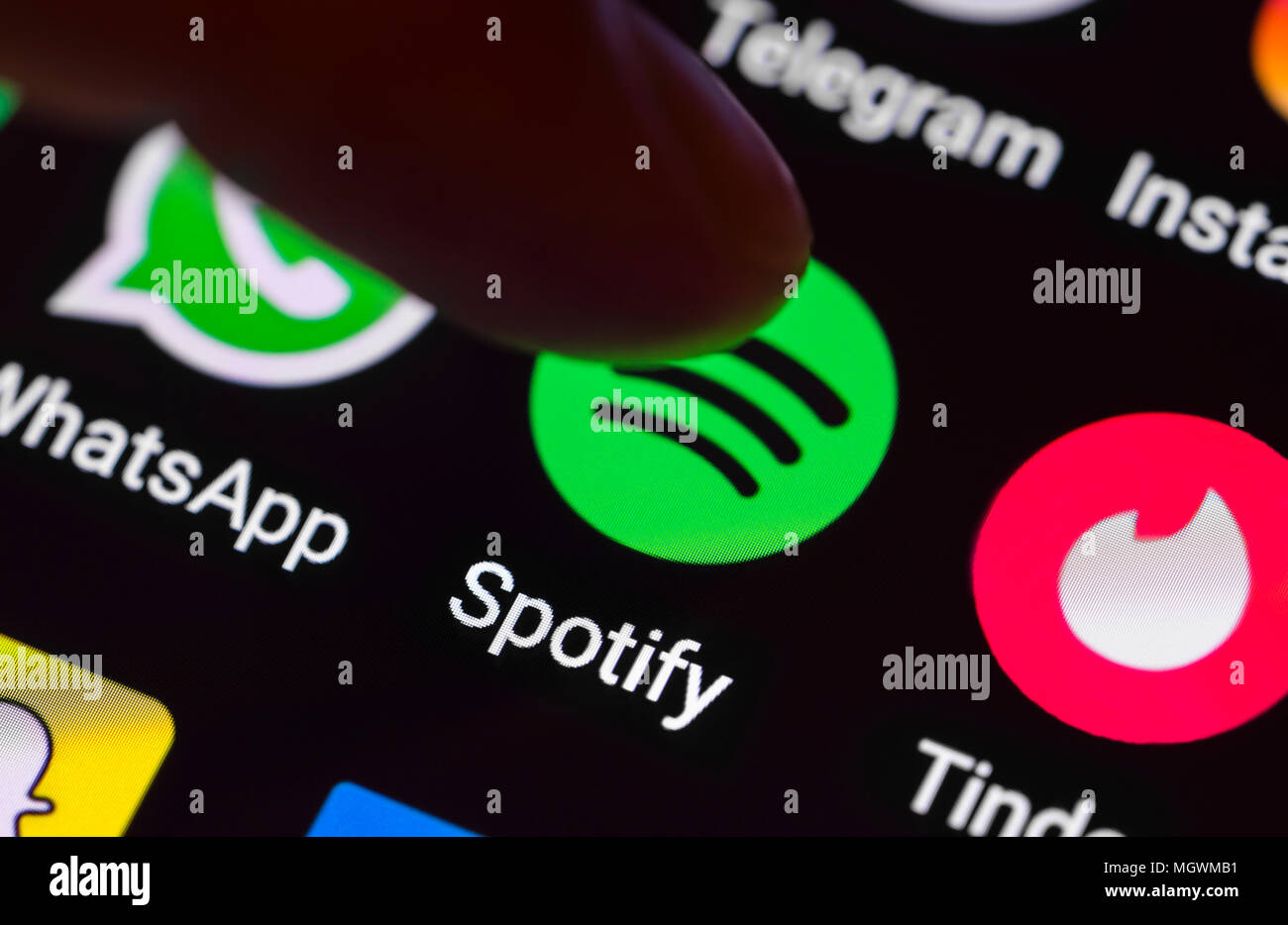Dito che preme una icona di collegamento per caricare il Spotify app su un tablet o lo schermo dello smartphone. Spotify pulsante. Foto Stock