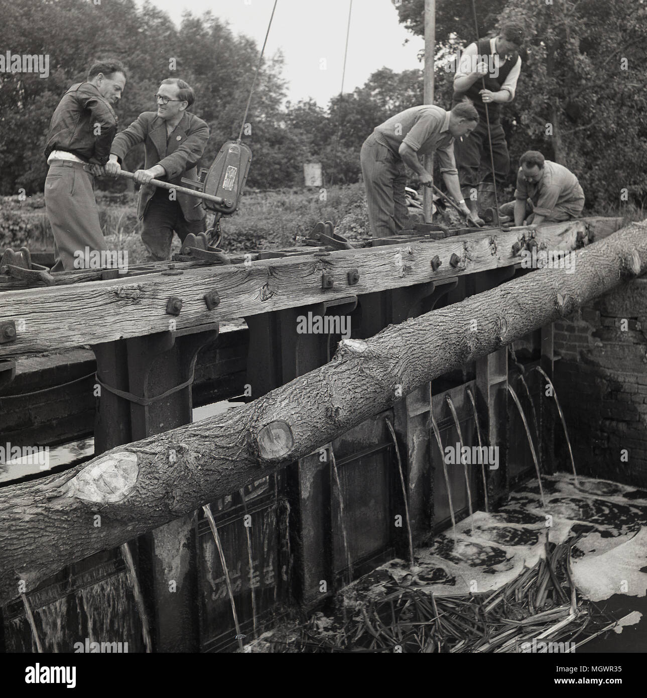 Degli anni Cinquanta, storico, volontari maschi di lavorare al di fuori alla riparazione di una saracinesca a canal lock, Inghilterra, Regno Unito. Foto Stock