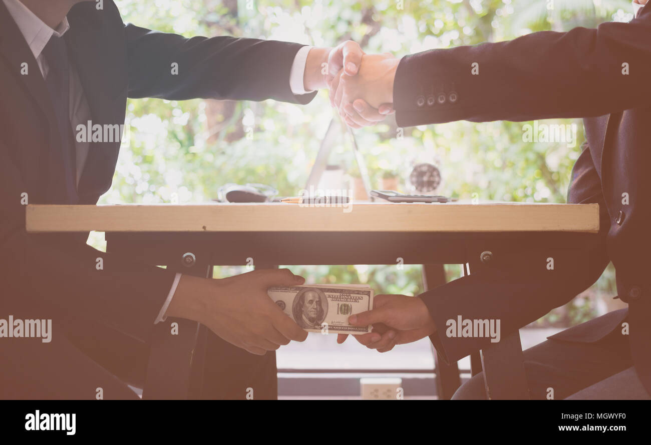 Concetto di corruzione. Primo piano di due uomini d'affari che scuotono Le Mani e ricevono denaro in dollari. Corrompere i soldi. Foto Stock