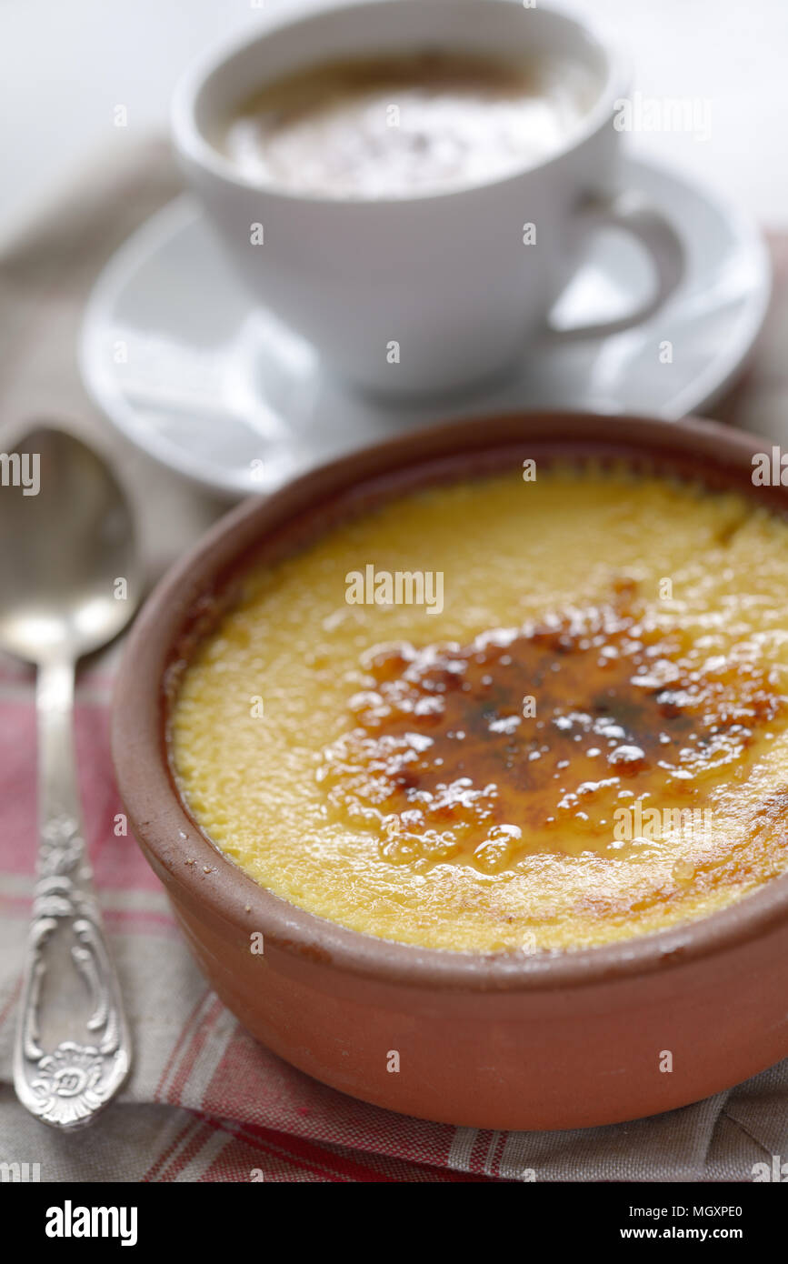 Crema catalana in una pentola e una tazza di caffè. Messa a fuoco selettiva su un centro di dessert Foto Stock