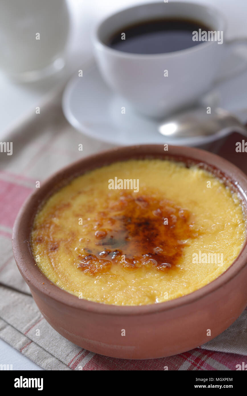 Crema catalana in una pentola e una tazza di caffè. Messa a fuoco selettiva su un centro di dessert Foto Stock