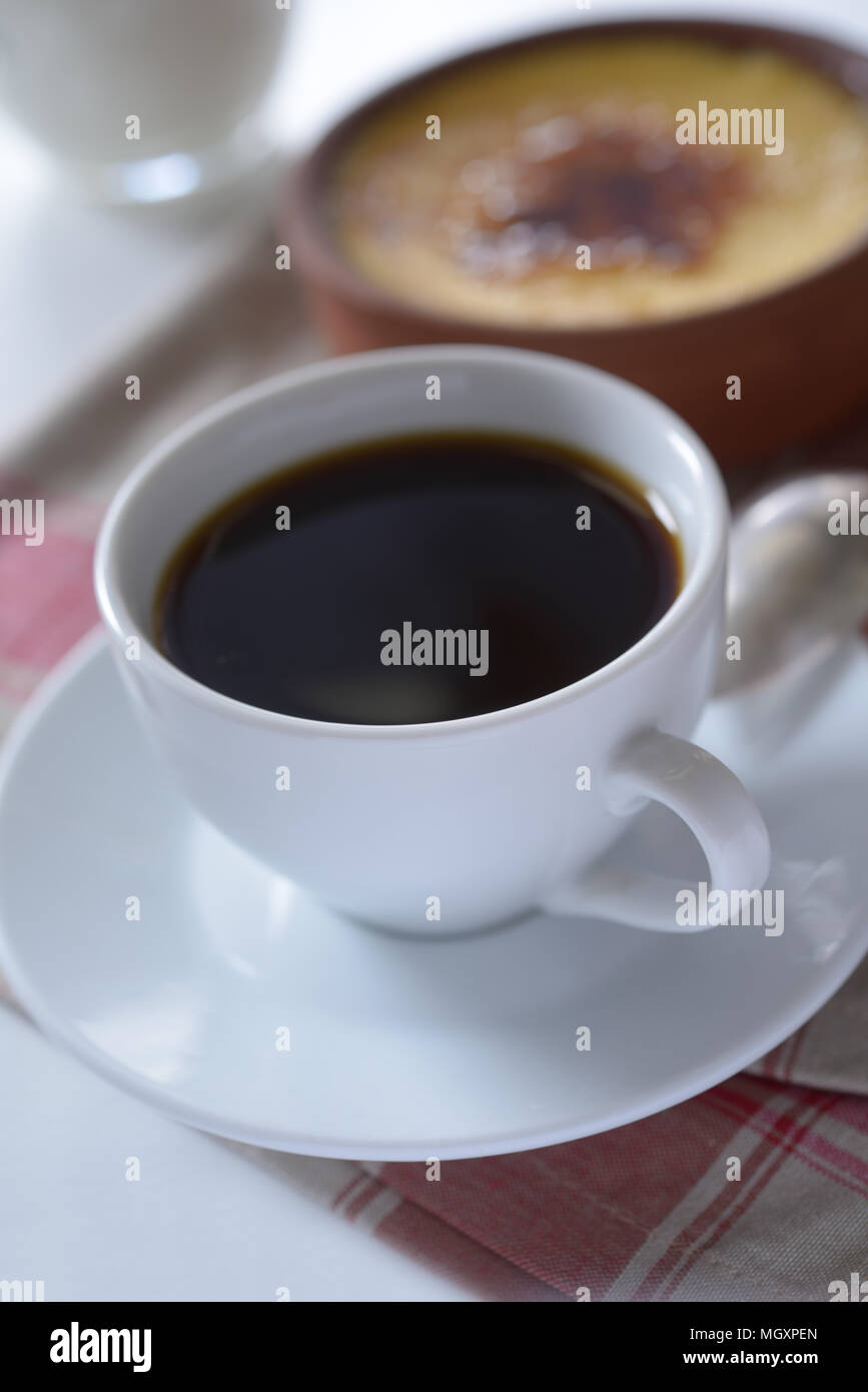 Tazza di caffè nero e crema catalana in una pentola. Messa a fuoco selettiva su un bordo anteriore della tazza Foto Stock