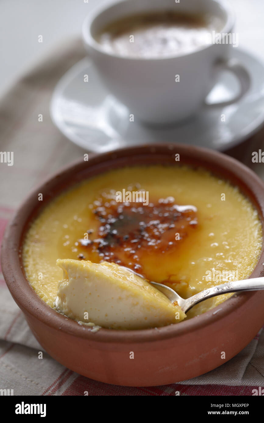 Crema catalana in una pentola e una tazza di caffè. Messa a fuoco selettiva su un centro di dessert Foto Stock