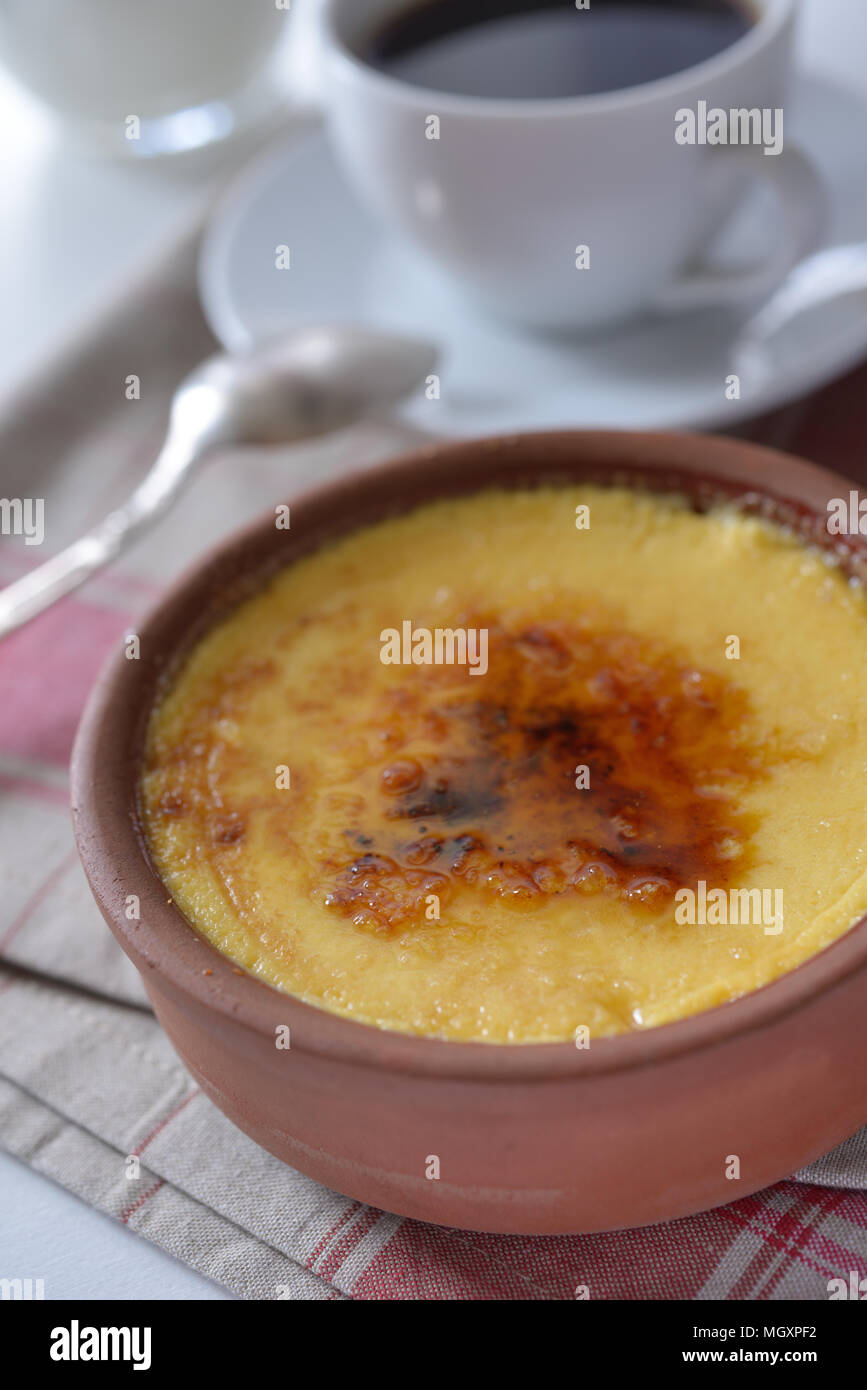 Crema catalana in una pentola e una tazza di caffè. Messa a fuoco selettiva su un centro di dessert Foto Stock