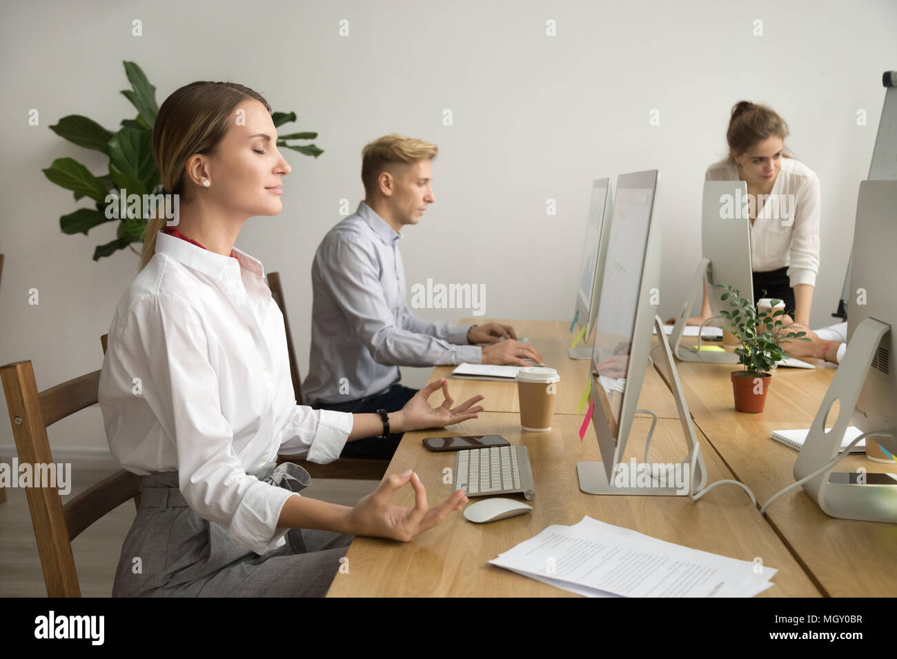 Calma felice imprenditrice meditando a scrivania da ufficio lavora con Foto Stock