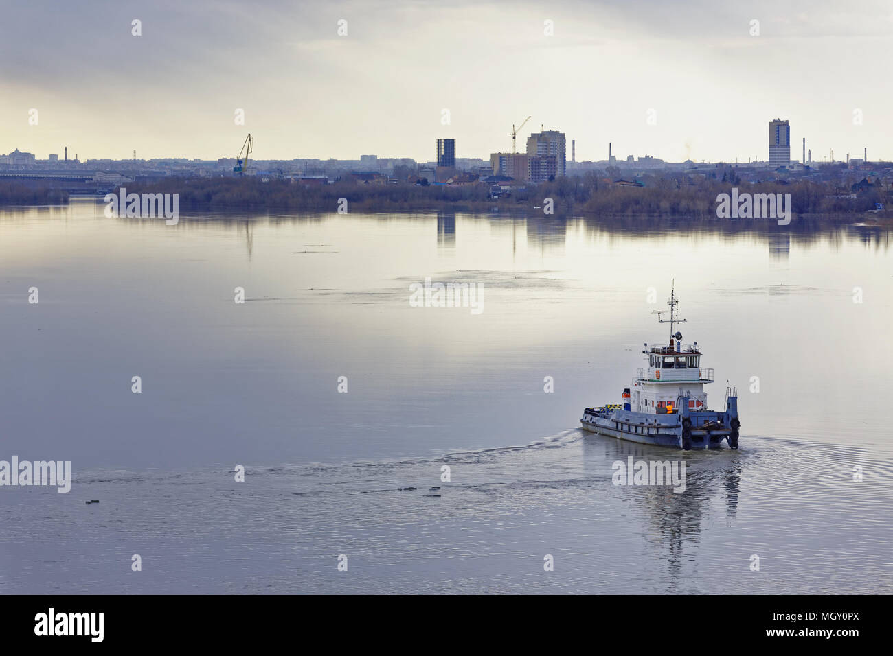Un rimorchiatore fluviale manovre su un fiume nelle vicinanze di una grande città. Inizio della primavera, un temporale si sta avvicinando Foto Stock