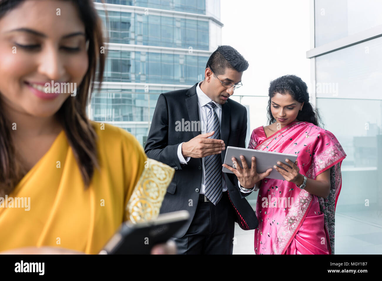 Tre Indian business persone utilizzando i moderni dispositivi interni Foto Stock