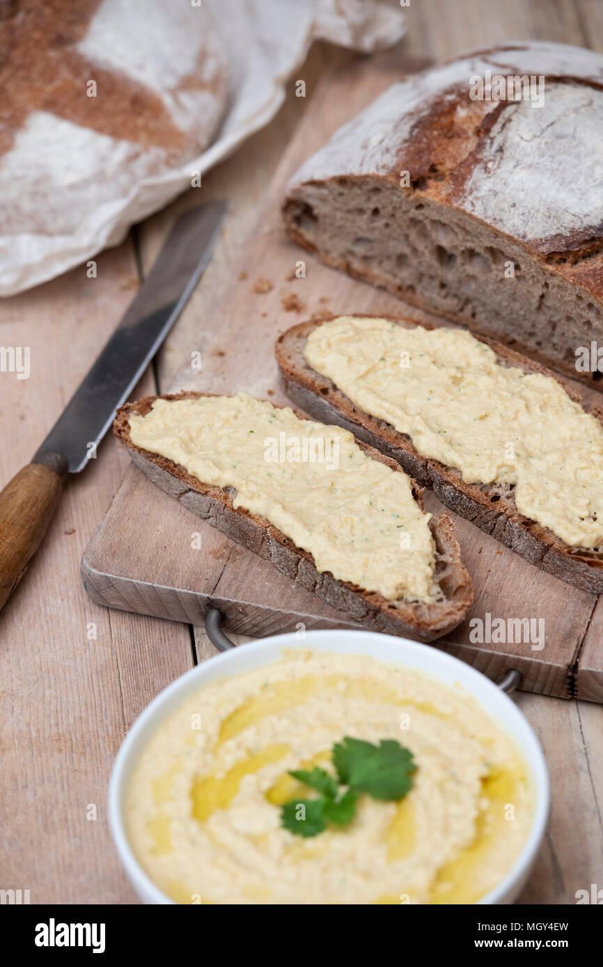 Pane di pasta acida e il farro pane di pasta acida con fatti in casa hummus su un pane a bordo. Regno Unito. Regno Unito Foto Stock