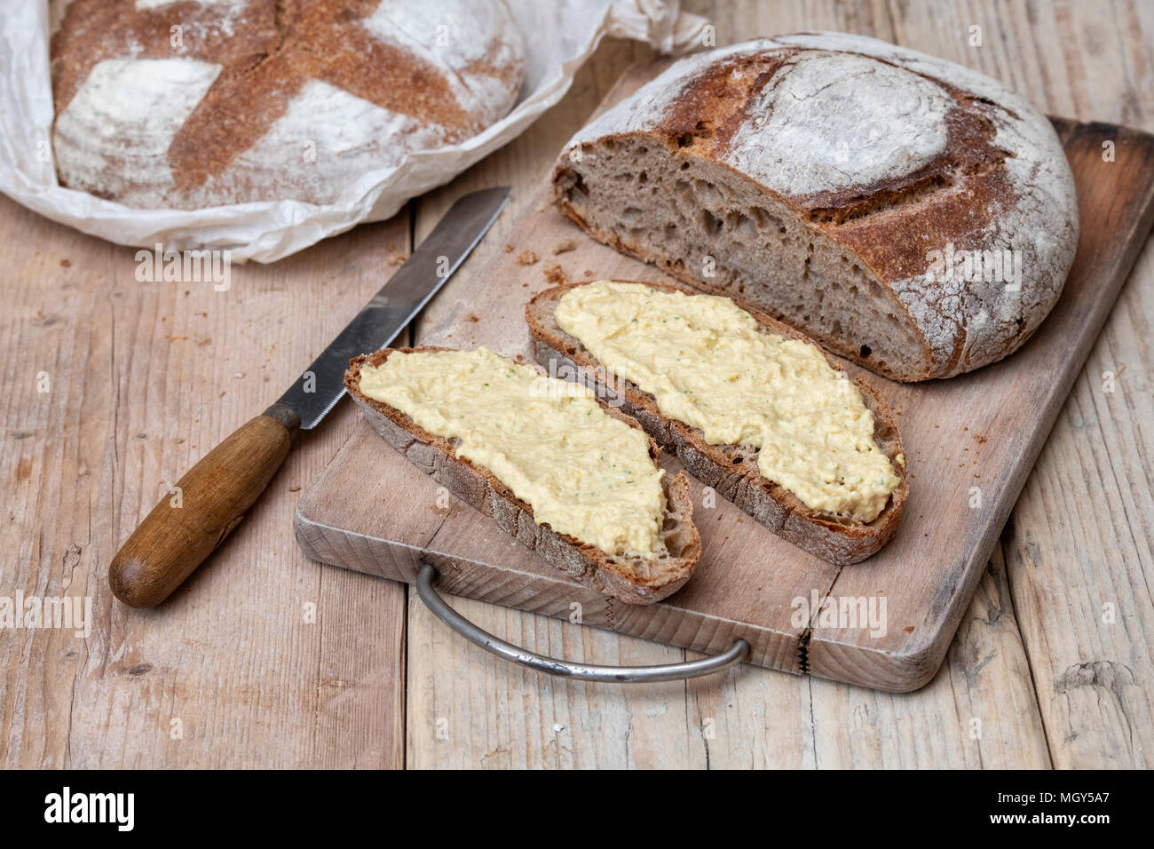 Pane di pasta acida e il farro pane di pasta acida con fatti in casa hummus su un pane a bordo. Regno Unito Foto Stock