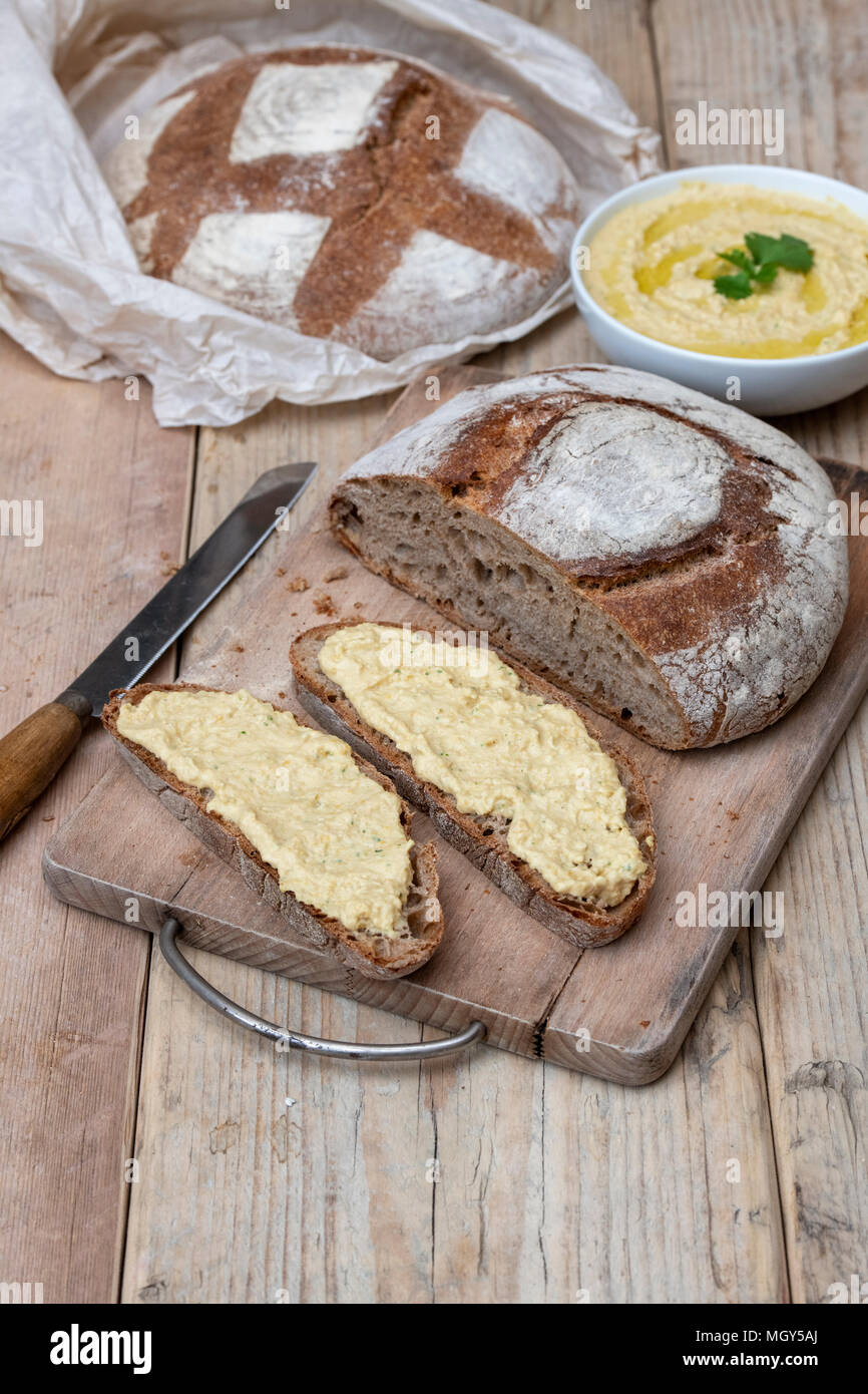 Pane di pasta acida e il farro pane di pasta acida con fatti in casa hummus su un pane a bordo. Regno Unito Foto Stock