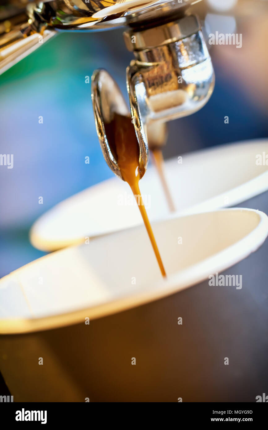 Close-up espresso fresco si riversa nella tazza monouso, Italiano macchina espresso. Cultura del caffè e professional per la preparazione di caffè, caffè per andare, servizio cateri Foto Stock